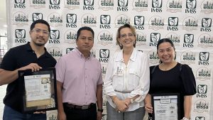 four people stand in front of a background with a repeating logo pattern