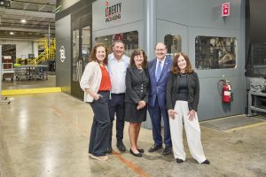 a photo of five people in front of manufacturing equipment